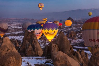 Sıcak hava balonları kış mevsiminde Turki 'deki Goreme Ulusal Parkı' nda, Kapadokya 'da gündoğumunda dağlardan havalanıyor. Goreme, Türkiye - 12 Şubat 2022.