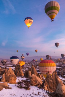 Sıcak hava balonları, Kapadokya 'daki Goreme Ulusal Parkı, Turki' deki gündoğumu sırasında dağların üzerinde uçar. Goreme, Türkiye - 12 Şubat 2022.