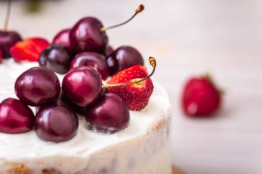 Çilek ve kiraz, hindistan cevizli cheesecake 'in üstünde..