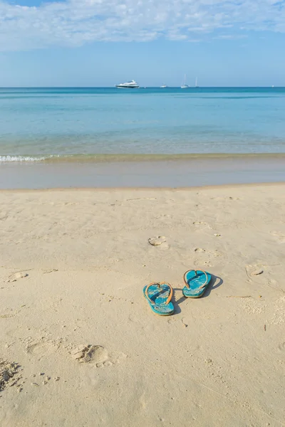 Zapatillas en el fondo de la playa de arena — Foto de Stock