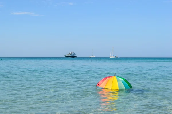 Färgglada paraply på havet vatten bakgrund med blå himmel — Stockfoto