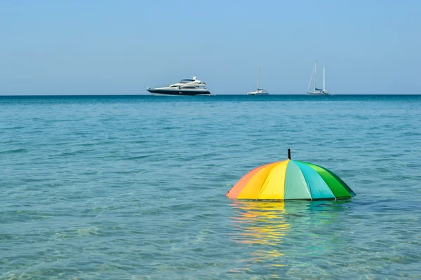 Ombrello colorato su sfondo acqua di mare — Foto Stock