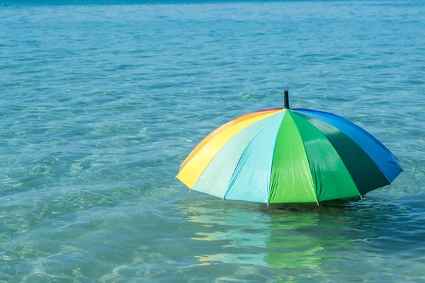 Closeup of colorful umbrella on sea water — Stock Photo, Image