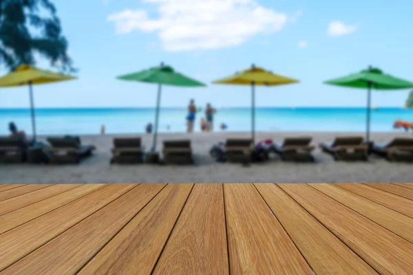 Trä bordsskiva på suddig färgglada paraply och vit sandstrand bakgrund med vissa personer — Stockfoto