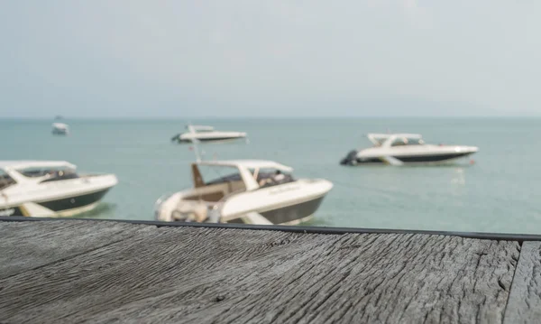 La vieja mesa de madera con vista a la playa y el fondo borroso de la lancha rápida - para el objeto presente o producto —  Fotos de Stock