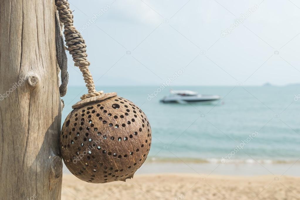 Lamp made from coconut shells with boat and beach blur background.