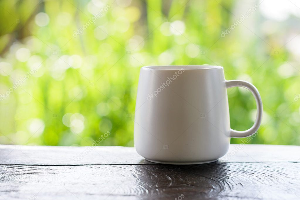 cup of coffee on table in cafe with Natural outdoors bokeh background