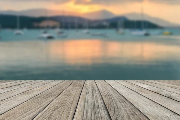 Ahşap masa üstü plaj ve yelkenli tekne arka plan üzerinde bulanık gün batımı ile
