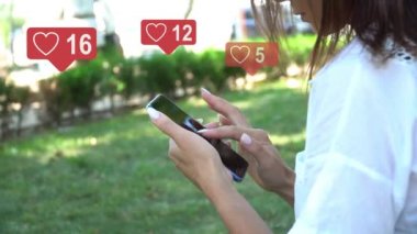 Güzel, genç ve güzel bir kız akıllı bir telefonla iletişim kuruyor, telefon ekranına metin yazıyor, sosyal ağ simgeleri aynı abone sayısına sahip, hızla artıyor