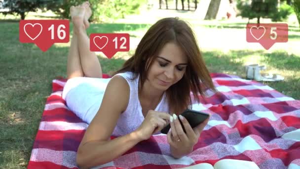 Una hermosa joven bonita interactúa con un teléfono inteligente, escribe texto en la pantalla del teléfono, iconos de redes sociales con el mismo número de suscriptores aumentan rápidamente — Vídeo de stock
