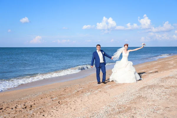 年轻的新娘和新郎在婚礼那天在海边散步 — 图库照片