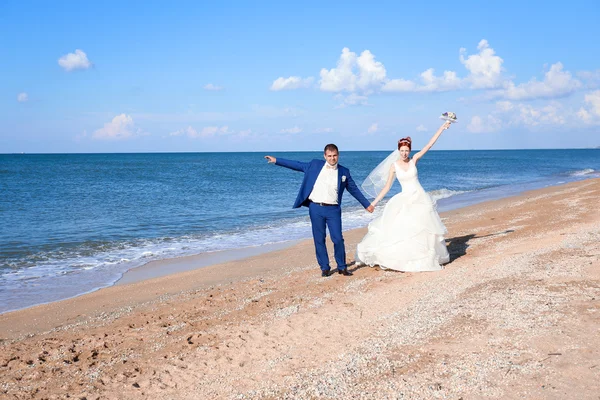 年轻的新娘和新郎在婚礼那天在海边散步 — 图库照片