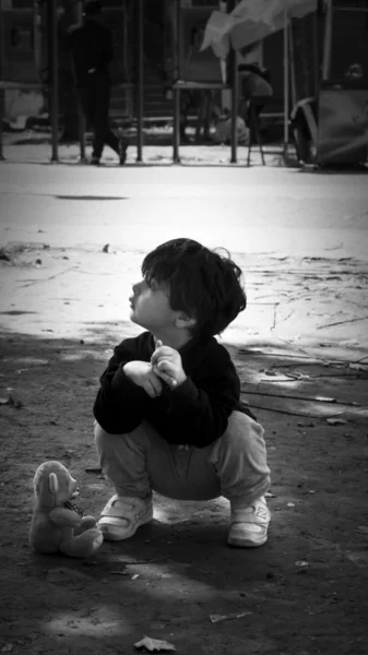 SERBIA, BELGRADE - September 14, 2015: Park at the station migrants from Syria have turned into a small city. Child in the dirt with teddy bear. Some have even set up tents and in which they reside, while most sleep under the open sky.