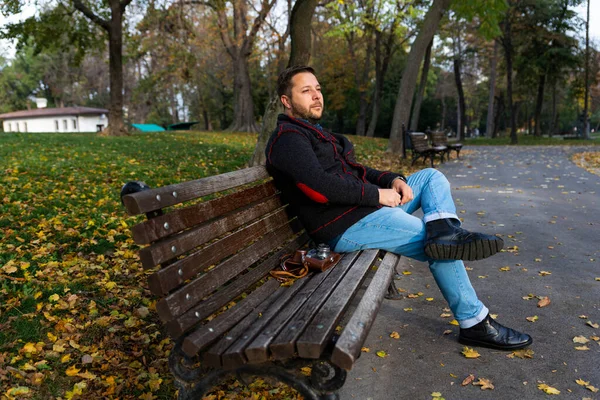 Uomo Sorridente Seduto Sulla Panchina Nel Parco Autunno Con Fotocamera — Foto Stock