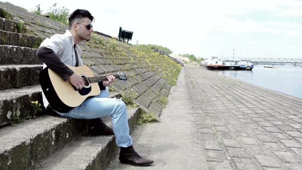 Hombre tocando la guitarra acustica en los muelles — Vídeo de stock