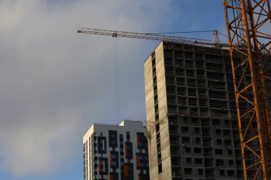 Yeni bir evin inşaatı. Tamamlanmamış beton gri bina. Pencereler camsız ve arka planda bir vinç.