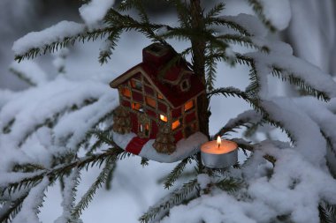 Noel ağacı oyuncak evi, pencereli ve ağaçta kalın bir kar tabakası ve yanan küçük bir Noel mumuyla kaplı bir kapı. Noel ve yeni yıl kompozisyonu.
