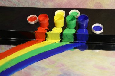 Parlak, siyah bir yüzeyde, kırmızı, yeşil, mavi bir kavanozda, akıntıda lekelenmiş bir leke olan, çok renkli boyalar. Yakın plan.