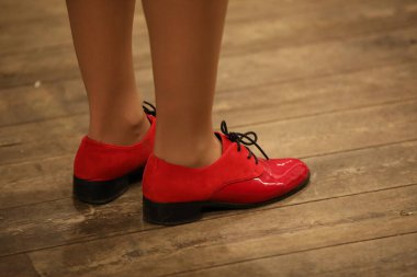 Kırmızı kadın ayakkabıları zarif kombinasyon deri kadife küçük topuk ve siyah bağcıklar. Güzel botlar içinde ayaklar eski ahşap zeminde duruyor.