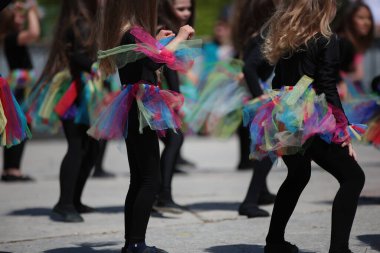 Bir grup genç dansçı kız sallanan renkli bir kostüm ve uzun saçla dans ediyorlar.