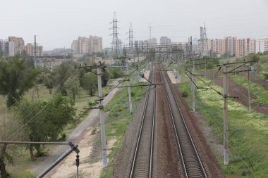Köprüden kırsal kesime giden demiryolu, iki demiryolu hattı ve ufukta evleri olan bir şehir.