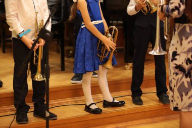 Bir müzik aleti olan küçük bir grup ilkokul öğrencisi sınıfta müzik öğreniyor. Öğretmenin önünde dikilip dersleri dikkatle dinliyorlar. Arkaplan resmi