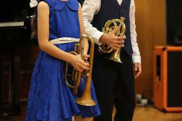 Kids playing the musical instrument trumpet.Couple of children little boy and girl in beautiful festive clothes perform at a concert.School music education and training concept