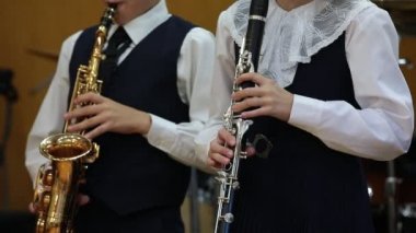 Çocuklar müzik enstrümanı çalıyor. Genç müzisyenlerin düeti. Kolej öğrencisi erkek saksafoncu kız ve klarnet çalan kız. Okul müzik eğitimi konsepti.