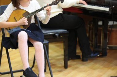 Çocuk domra oynuyor. Rus folk müzik enstrümanlı kız öğrenci müzisyen sınıftaki öğretmenle birlikte bir dizi üzerinde müzik eğitimi alıyor. Geliştirme ve okul kavramı.
