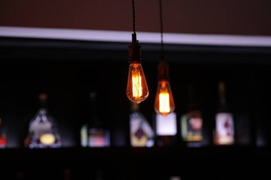 Bulanık şişe vitriniyle gece barında lamba. Seçici odak noktası. İçki rafı olan klasik bar arka planı.