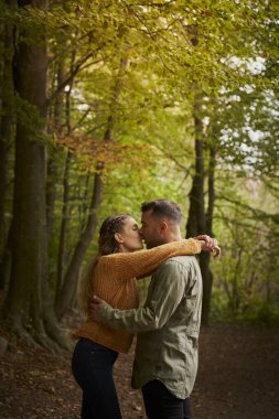 Mutlu genç çift, güzel bir sonbahar gününde güzel bir yolda birbirlerini öpüyorlar..