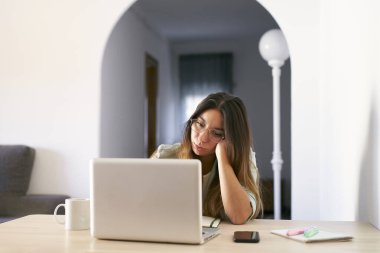 Evde dizüstü bilgisayarla çalışan yorgun ve stresli bir kadının ön görüntüsü..