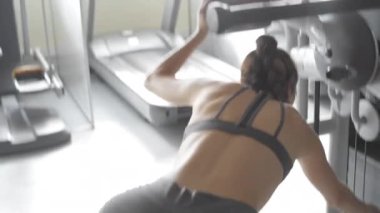 Spor salonundaki genç kadın basın makinesine döndü ve baldırlarını çalıştırmak için egzersiz yapmaya başladı..