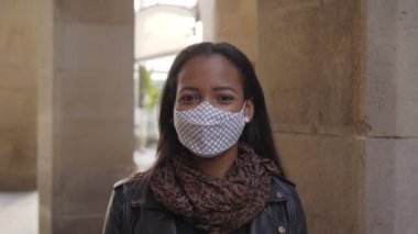 Dışarıdaki kameraya bakan yüz maskesi takan Afro-Amerikalı bir kadının portresi. Covid19 salgınından dolayı koronavirüs zamanlarında yeni bir normal..