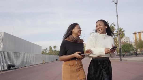 Dos Chicas Negras Caminando Una Ciudad Mientras Usan Teléfono Móvil — Vídeos de Stock