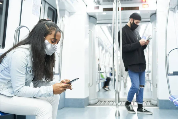 Toplu taşımacılıktaki gençler teknoloji tarafından kaçırıldı. Afro-Amerikalı bir kız ve beyaz bir oğlan metrodaki akıllı telefonu kullanıyorlar..
