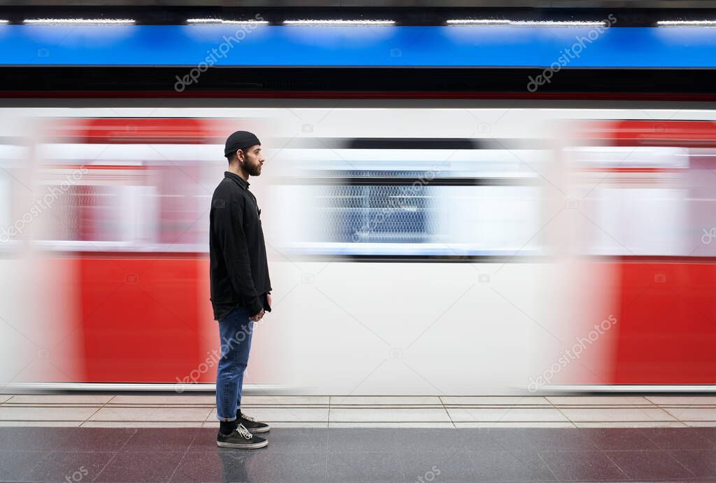 Young man on his side with a mask on the subway platform. The movement of the subway caravan in the background. Copy space.