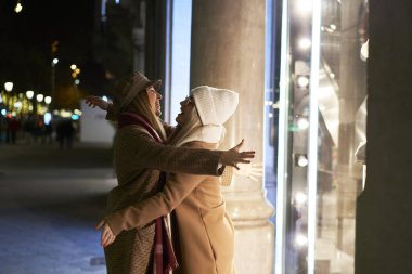 İki genç kadın, birbirlerini tekrar gördükleri için mutlu ve heyecanlılar, birbirlerini coşkuyla kucaklıyorlar. Gece bir şehirdeler ve kışlık kıyafetler giyiyorlar. Tekrar birlikteyiz