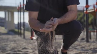 Bir adamın ellerine magnezyum koyarken, halter egzersizleri yapmaya hazırlanırken. Ellerinin arasında kumla.