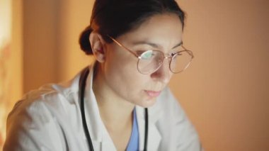 Vurulma yüzünden bilgisayarda çalışan bir kadının ellerine kadar gidiyor. Monitörün ışığıyla aydınlatılmış.