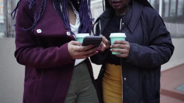 两名使用外面电话的年轻妇女的手部特写 在办公室休息的时候 他们一边喝咖啡 一边用智能手机评论他们正在看的东西 — 图库视频影像