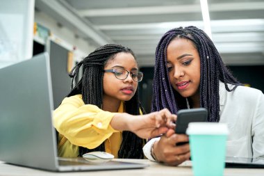 Afrikalı Amerikalı iş arkadaşları ofis toplantılarında iş hakkında konuşurlar. Akıllı bir telefonla projeyi gözden geçiriyorlar..