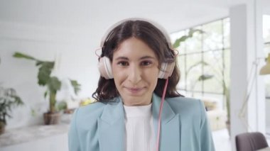 Takım elbiseli güzel bir ofis çalışanının portresi ofiste kameraya bakıyor kulaklık takıp iş molalarının keyfini çıkarıyor. Çılgın insanlar, evde eğlence ve yaşam tarzı konsepti..