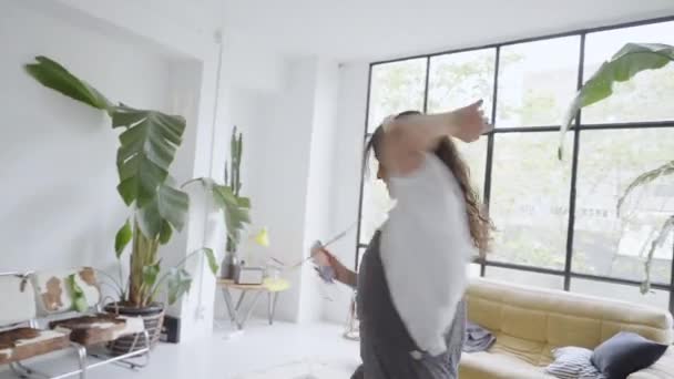 Ευτυχισμένη νεαρή γυναίκα χιλιετή χορεύει στο σπίτι διασκεδάζοντας γιορτάζοντας με διασκεδαστικές χορευτικές κινήσεις απολαμβάνοντας την ελευθερία το πρωί του Σαββατοκύριακου. — Αρχείο Βίντεο