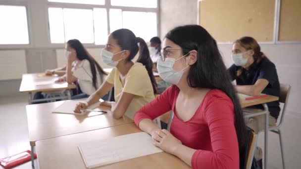 Grupo de estudiantes de diferentes etnias sentados en clase atendiendo al profesor. Jóvenes estudiando en la universidad sentados en sus escritorios. — Vídeos de Stock