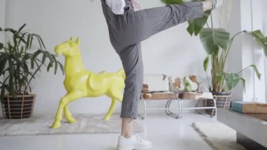 Mutlu genç kadın evde dans edip kulaklıkla müzik dinliyor. Neşeli kadın evde eğlenceyi kutluyor. Yavaş çekim.