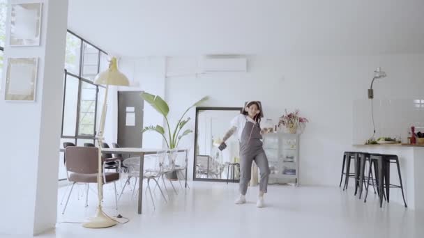 Mooie jonge vrouw die thuis danst en naar muziek luistert op een koptelefoon. Plezier hebben in de woonkamer, springen en draaien, zich alleen gelukkig voelen, in slow motion. — Stockvideo