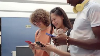 Bir grup öğrenci cep telefonu kullanıyor. Lisedeki gençler teknolojiyle bağlantılı..