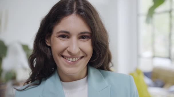 Young business woman turning her eyes to camera and smiling. Portrait of the face of a cheerful happy latina woman looking at the camera with a smile. — стоковое видео