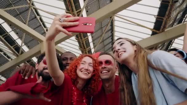 Fans die een selfie maken terwijl ze vanuit een stadion voor hun sportteam juichen. Vrolijke mannelijke en vrouwelijke fans die een video opnemen met hun telefoon tijdens het kijken naar de wedstrijd in het stadion. — Stockvideo